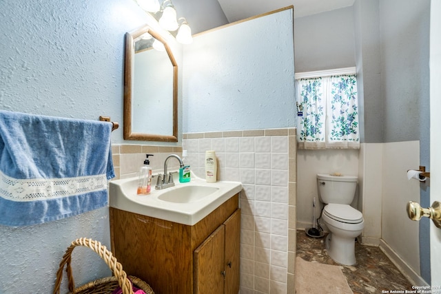 bathroom with vanity, tile walls, and toilet