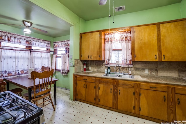 kitchen featuring a ceiling fan, visible vents, light floors, a sink, and black range with gas cooktop