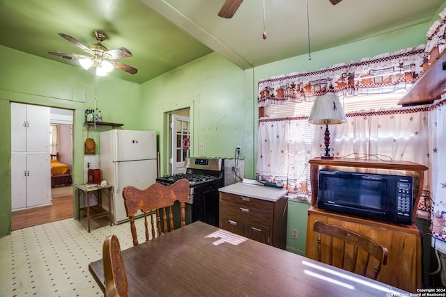 kitchen featuring stainless steel gas range oven, ceiling fan, freestanding refrigerator, and black microwave