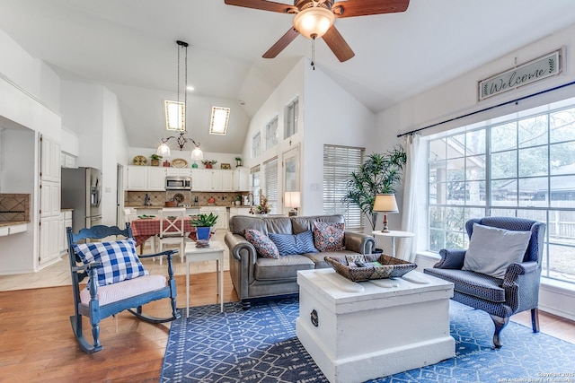 living area featuring ceiling fan with notable chandelier, high vaulted ceiling, and wood finished floors