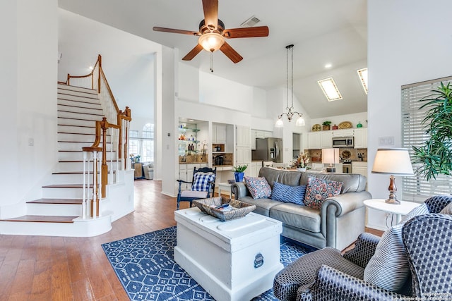 living room with visible vents, high vaulted ceiling, stairway, wood-type flooring, and ceiling fan