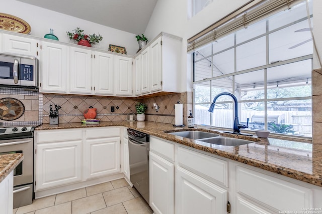 kitchen featuring tasteful backsplash, light tile patterned flooring, stone countertops, stainless steel appliances, and a sink