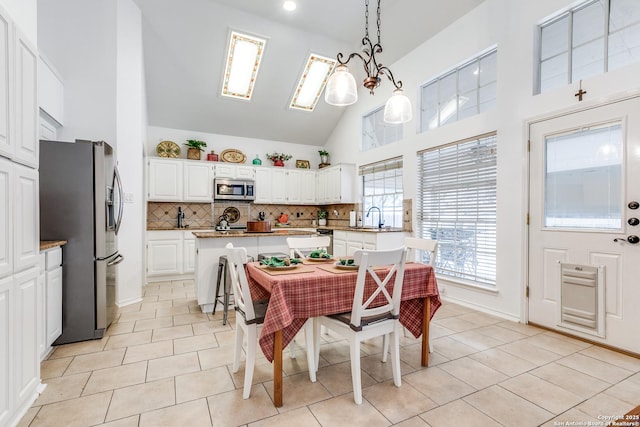 dining area featuring baseboards, high vaulted ceiling, and light tile patterned flooring