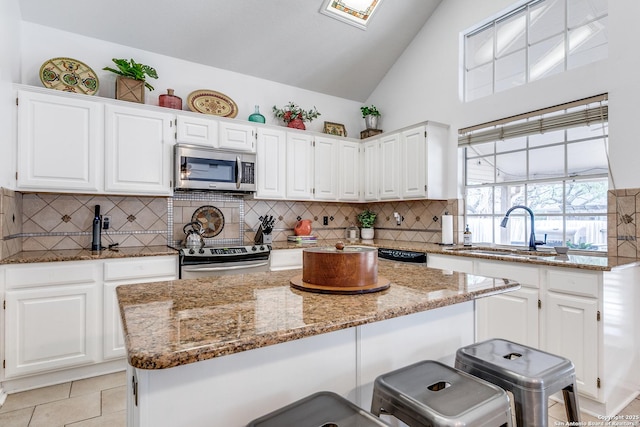 kitchen featuring light stone counters, white cabinetry, stainless steel appliances, and a sink