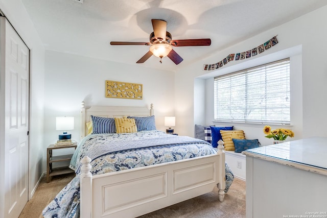 bedroom featuring baseboards, light colored carpet, a closet, and ceiling fan