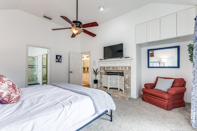 carpeted bedroom with visible vents, connected bathroom, vaulted ceiling, a fireplace, and a ceiling fan