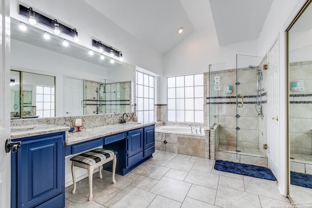 bathroom featuring vaulted ceiling, double vanity, a stall shower, a bath, and a sink