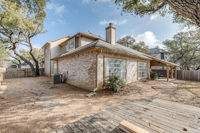 back of house with a fenced backyard, a chimney, a deck, central air condition unit, and brick siding