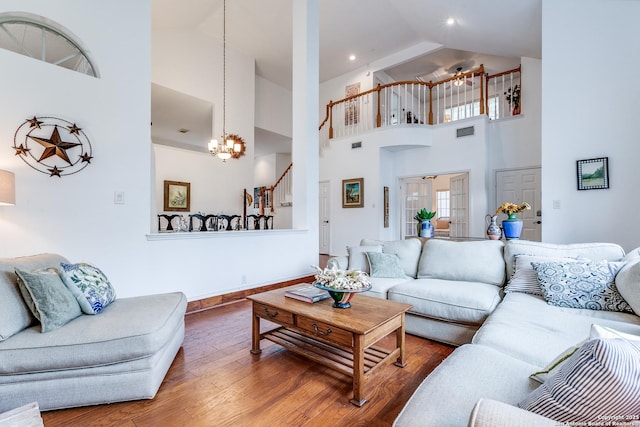 living room with visible vents, high vaulted ceiling, wood finished floors, and stairway