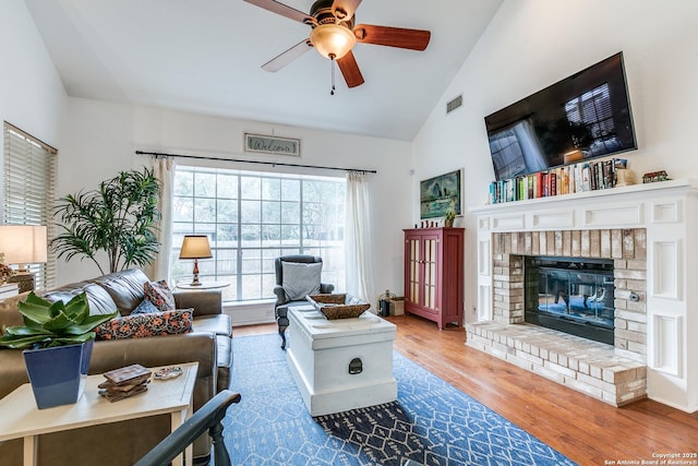 living room featuring visible vents, a ceiling fan, wood finished floors, a fireplace, and lofted ceiling