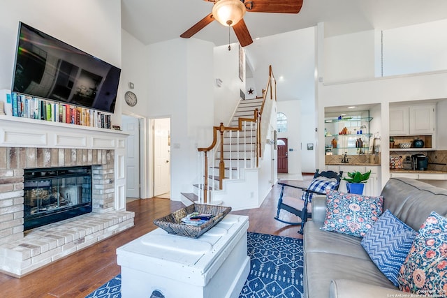 living area with stairway, wood finished floors, ceiling fan, and a towering ceiling