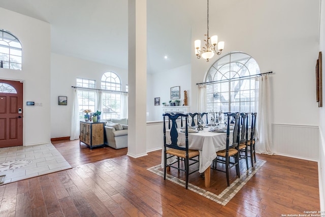 dining area featuring a wainscoted wall, a towering ceiling, and hardwood / wood-style floors