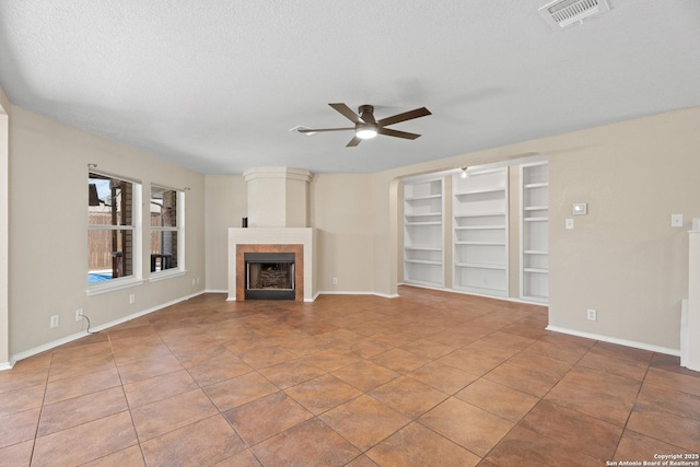 1967 Club Xing, New Braunfels, TX 78130 - unfurnished living room with visible vents, baseboards, a tile fireplace, a textured ceiling, and a ceiling fan