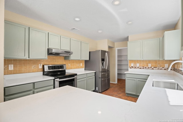 1967 Club Xing, New Braunfels, TX 78130 - kitchen featuring under cabinet range hood, a sink, backsplash, appliances with stainless steel finishes, and light countertops