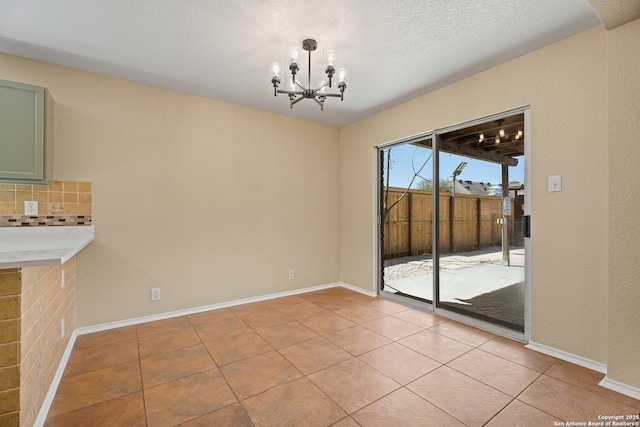 1967 Club Xing, New Braunfels, TX 78130 - unfurnished dining area with baseboards, a textured ceiling, an inviting chandelier, and light tile patterned flooring