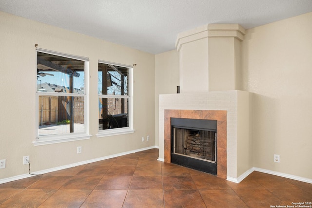 1967 Club Xing, New Braunfels, TX 78130 - unfurnished living room featuring a tiled fireplace, a textured ceiling, and baseboards