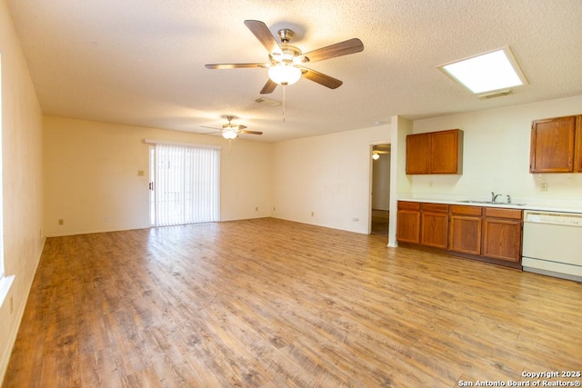 unfurnished living room with a textured ceiling, visible vents, light wood finished floors, and a sink