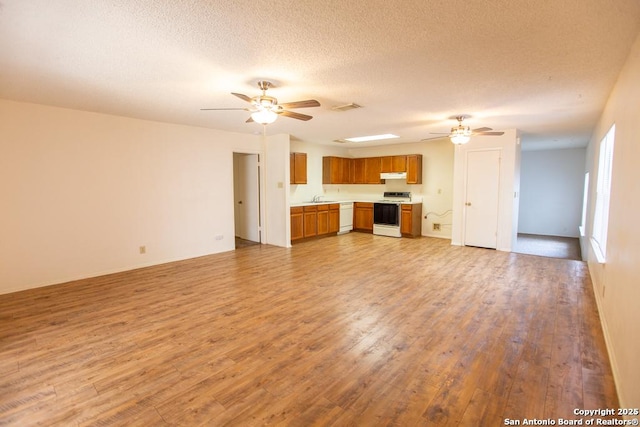 unfurnished living room featuring a ceiling fan, visible vents, light wood finished floors, and a textured ceiling