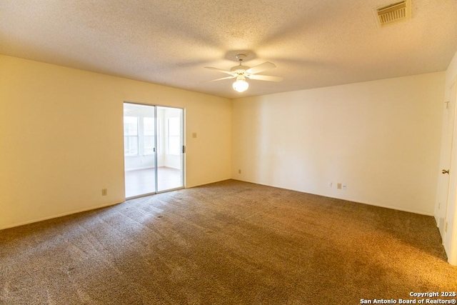 spare room with a ceiling fan, visible vents, carpet floors, and a textured ceiling