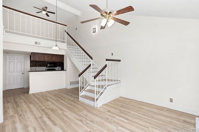 unfurnished living room featuring visible vents, stairs, a ceiling fan, and wood finished floors