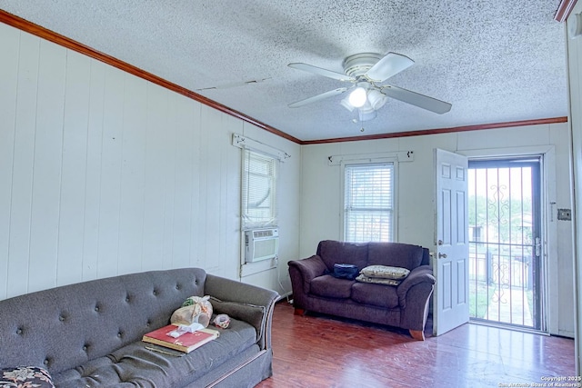 living area with ornamental molding, cooling unit, wood finished floors, a textured ceiling, and a ceiling fan