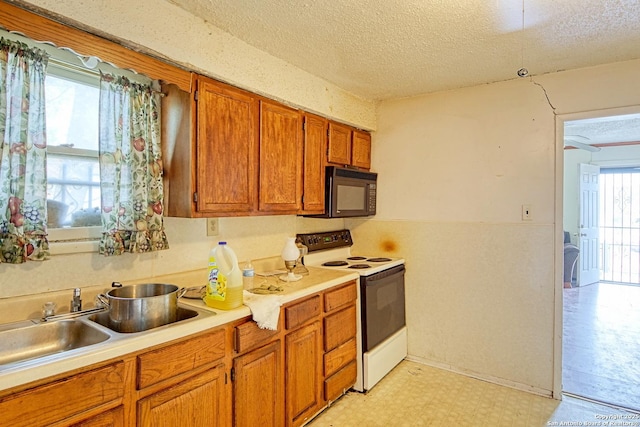 kitchen featuring black microwave, light floors, brown cabinets, a textured ceiling, and white electric range