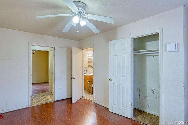 unfurnished bedroom featuring ceiling fan, connected bathroom, wood finished floors, and a textured ceiling