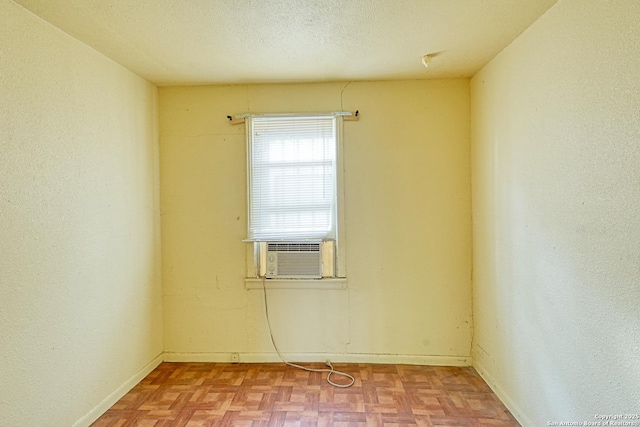 spare room with cooling unit, baseboards, and a textured ceiling