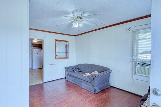 sitting room featuring ceiling fan, a textured ceiling, wood finished floors, and ornamental molding