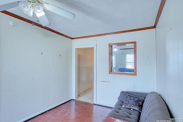 interior space featuring ornamental molding, a textured ceiling, a ceiling fan, and wood finished floors