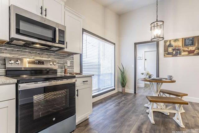 kitchen with dark wood finished floors, decorative backsplash, appliances with stainless steel finishes, and white cabinetry