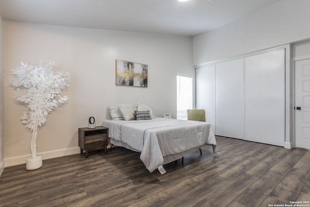 bedroom with a closet, baseboards, and dark wood-type flooring