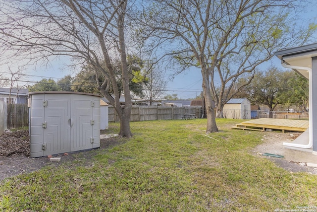 view of yard featuring a wooden deck, a storage unit, a fenced backyard, and an outdoor structure