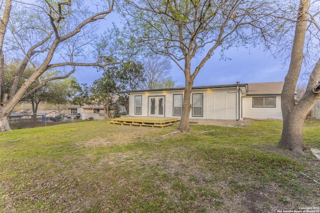 back of house with french doors, fence, and a lawn