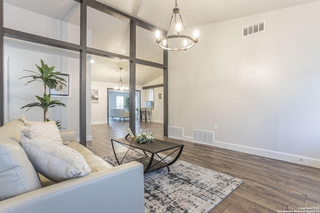 living room featuring a notable chandelier, visible vents, and wood finished floors