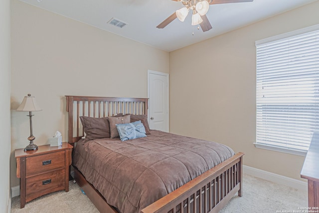 bedroom with visible vents, baseboards, light colored carpet, and ceiling fan