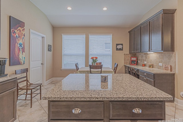 kitchen featuring lofted ceiling, backsplash, dark brown cabinets, and a kitchen island