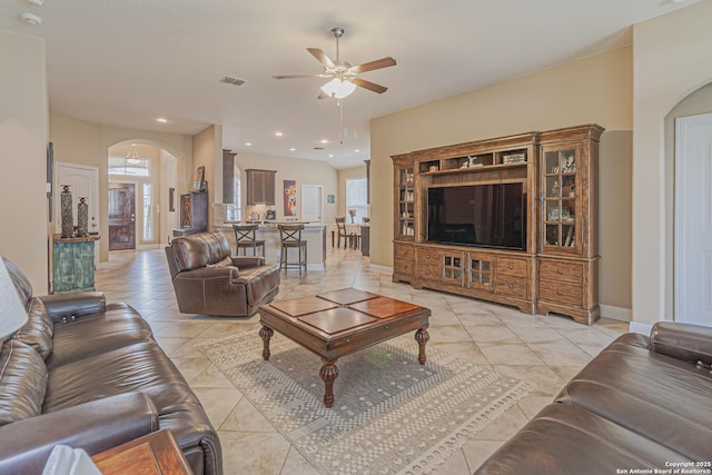 living room with arched walkways, visible vents, plenty of natural light, and ceiling fan