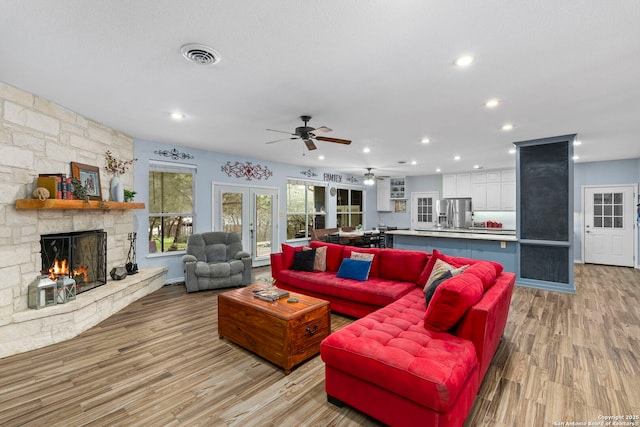 living area featuring light wood-type flooring, visible vents, recessed lighting, a fireplace, and ceiling fan