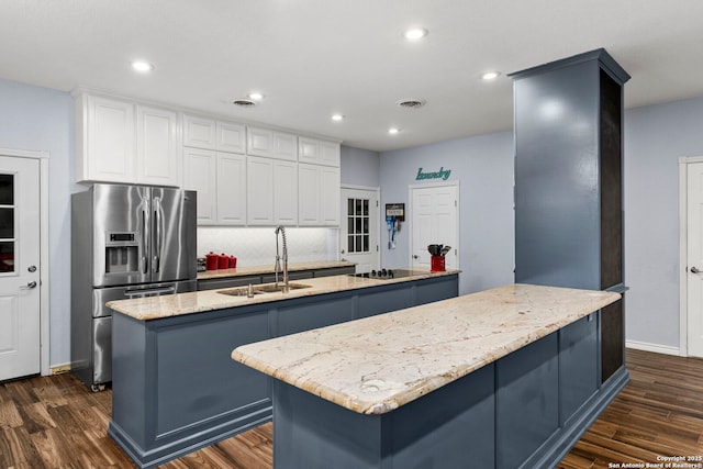 kitchen with a kitchen island with sink, visible vents, stainless steel fridge with ice dispenser, dark wood finished floors, and a sink