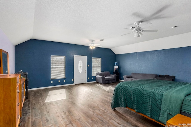 bedroom with lofted ceiling, wood finished floors, baseboards, and a textured ceiling