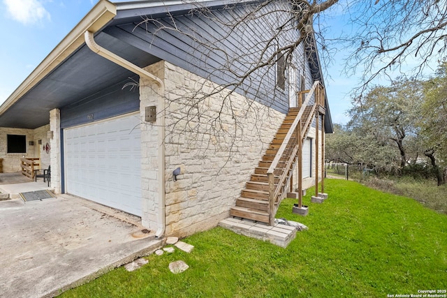 view of side of home with stairs, a yard, and an attached garage