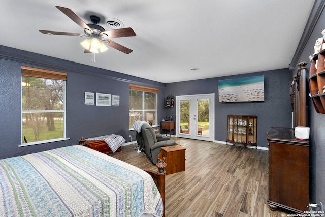 bedroom featuring multiple windows, french doors, baseboards, and wood finished floors