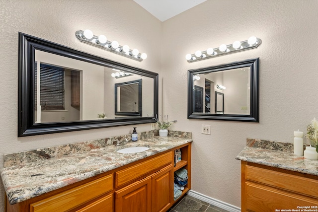 bathroom featuring tile patterned floors, baseboards, vanity, and a textured wall