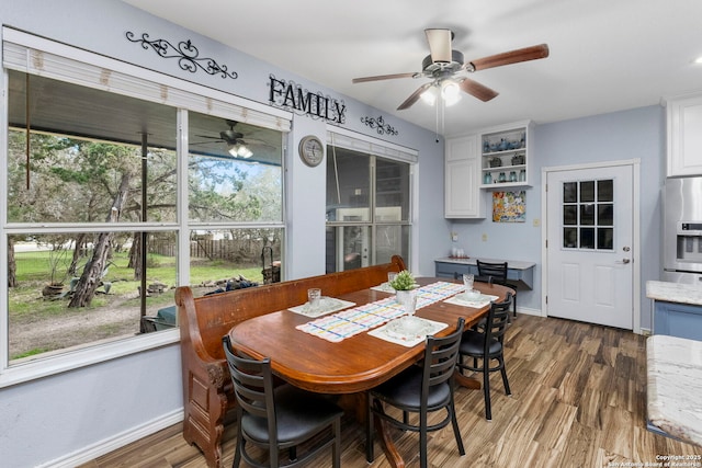 dining space with baseboards, a ceiling fan, and wood finished floors