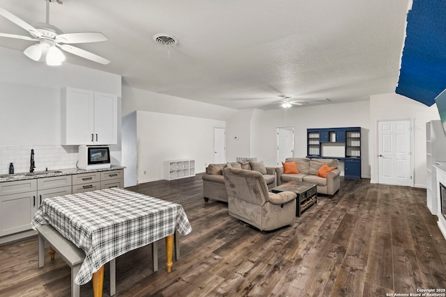 living area featuring dark wood finished floors, visible vents, and a ceiling fan