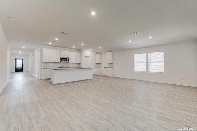 kitchen featuring stainless steel microwave, open floor plan, tasteful backsplash, and visible vents