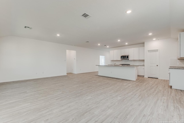 kitchen with open floor plan, stainless steel microwave, light wood-type flooring, and visible vents