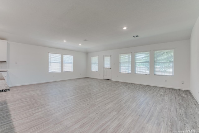 unfurnished living room with recessed lighting, light wood-type flooring, and baseboards