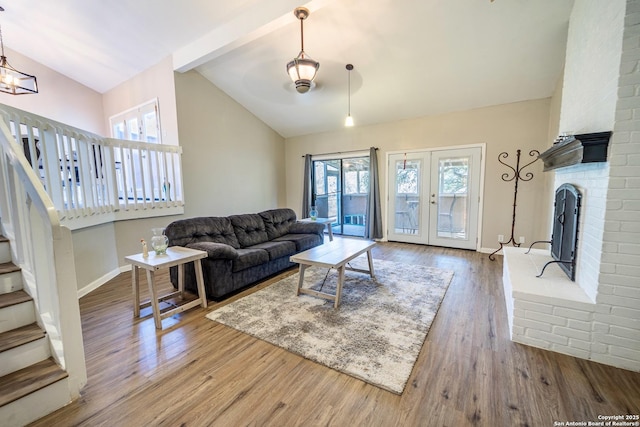 living room with french doors, lofted ceiling, wood finished floors, and stairs